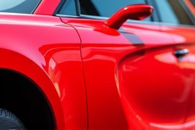 Sparkling clean red sedan after a thorough wash, reflecting sunlight